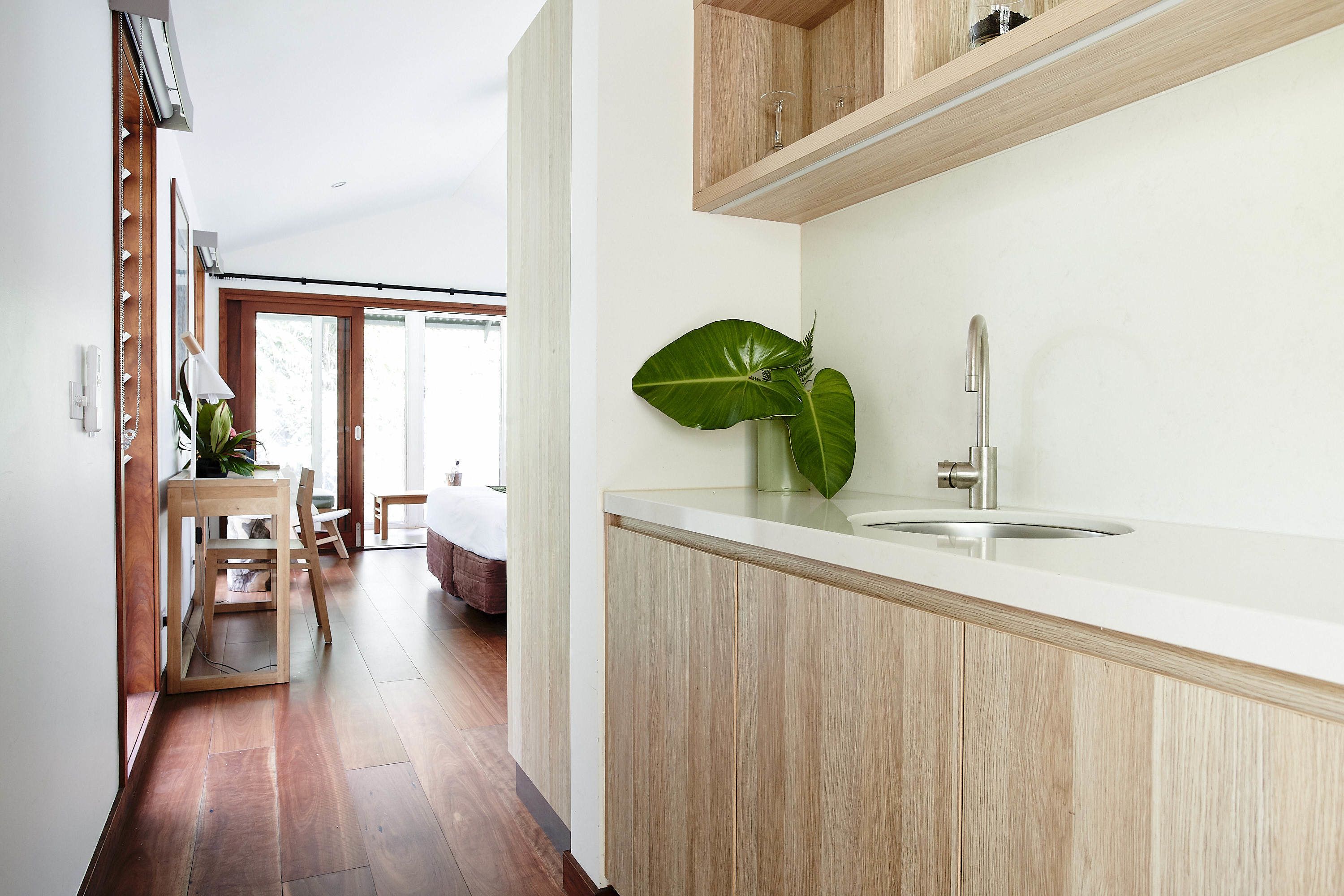 Une cuisine moderne avec des meubles en bois, un plan de travail blanc et une grande plante verte.