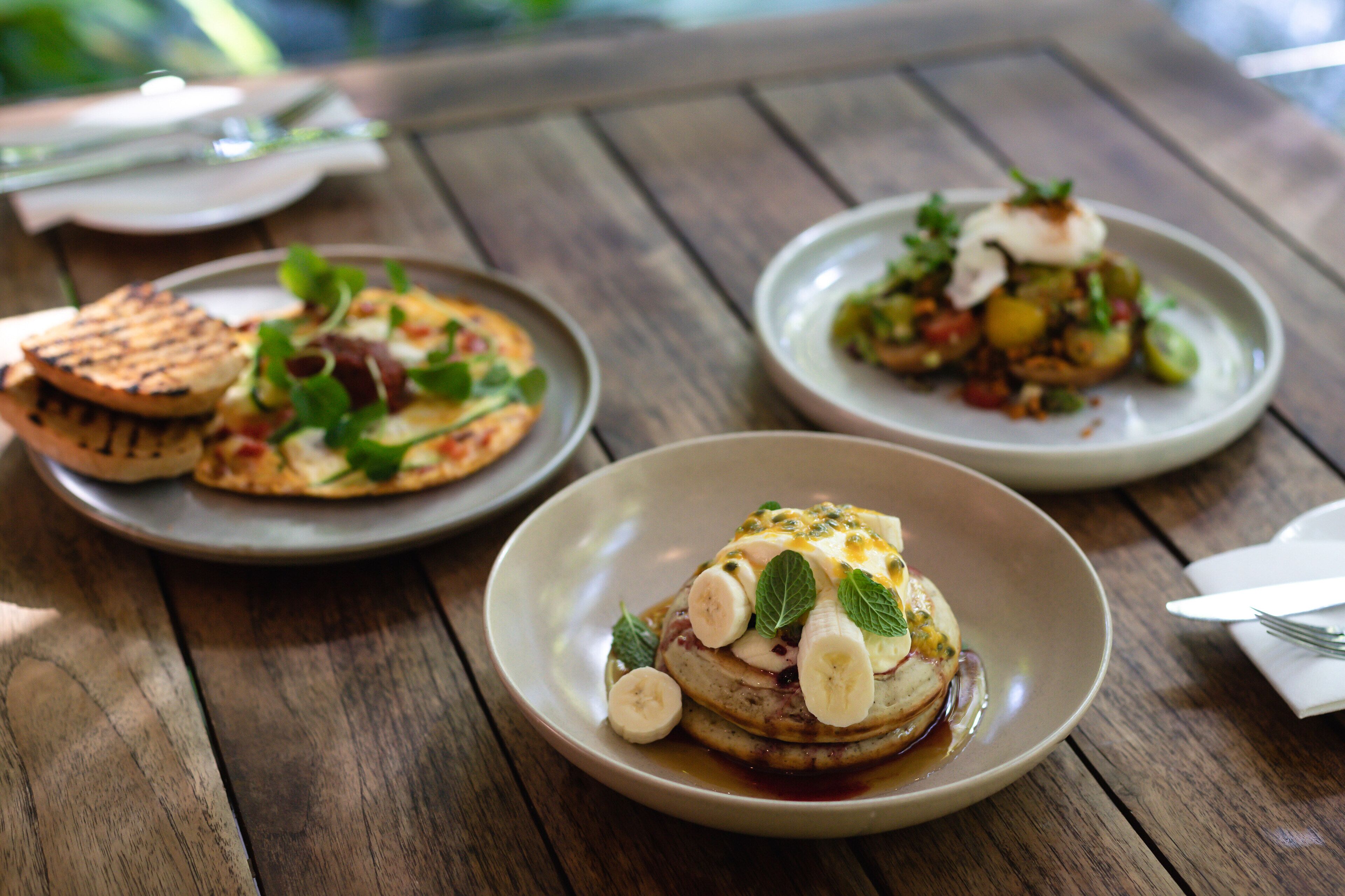 Three plates of food on a wooden table.
