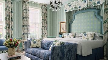 Une chambre à coucher avec un grand lit, un canapé bleu, un lustre et un papier peint à rayures.
