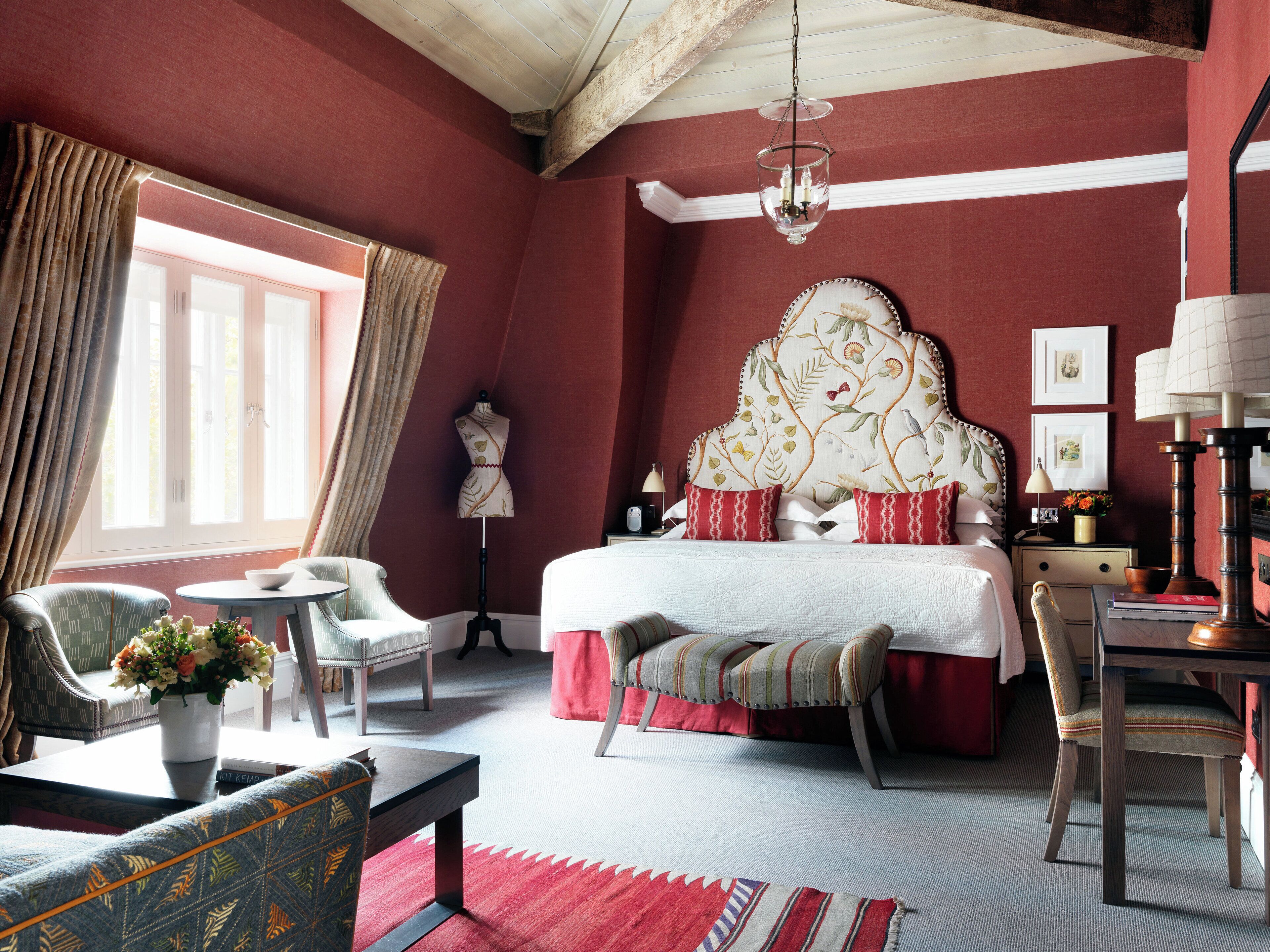 A bedroom with a large bed, a chair, a table, and a lamp.