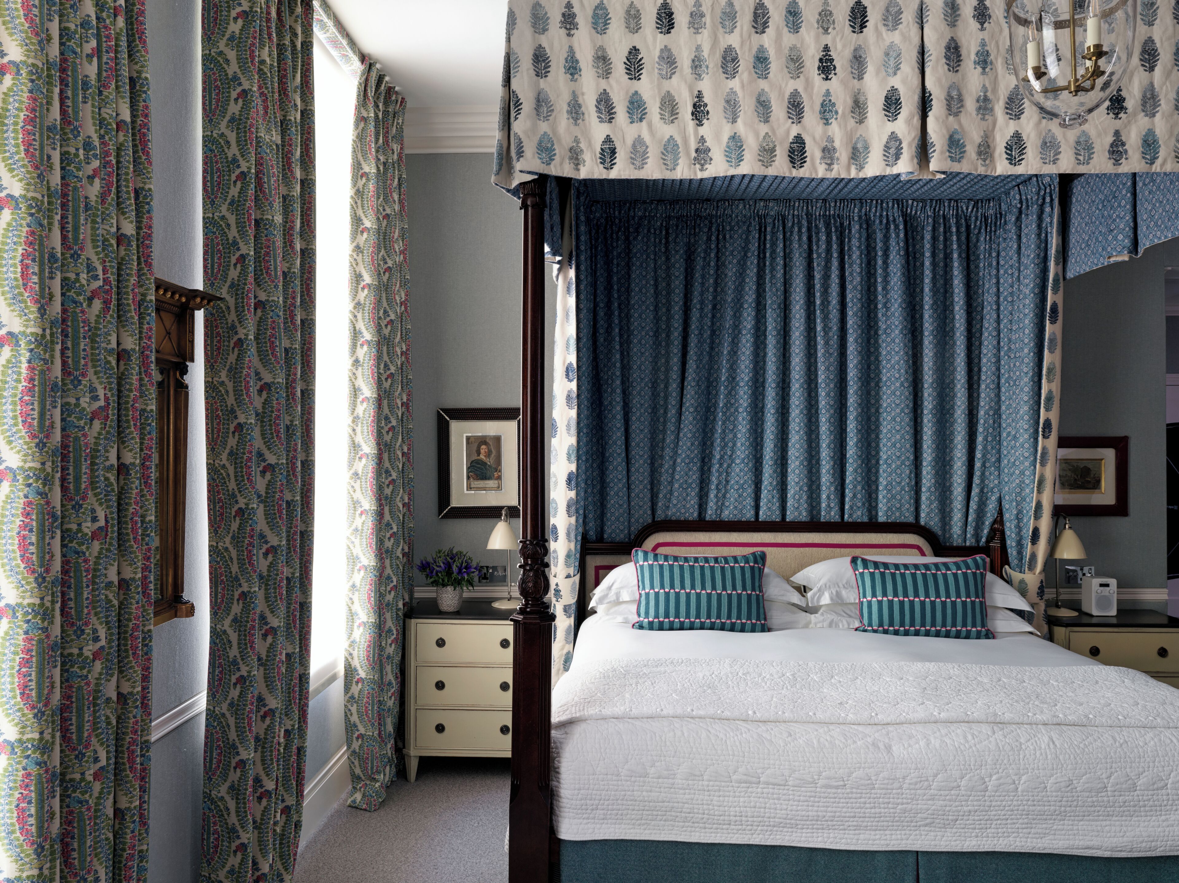 Une chambre à coucher avec un lit à baldaquin, une table de chevet, une commode et des rideaux à motifs.