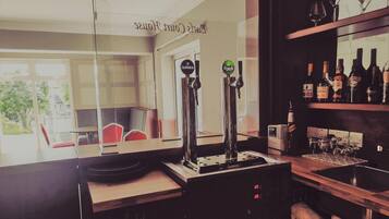 A bar area with two Guinness taps, a shelf with various bottles, and a view of the outside.