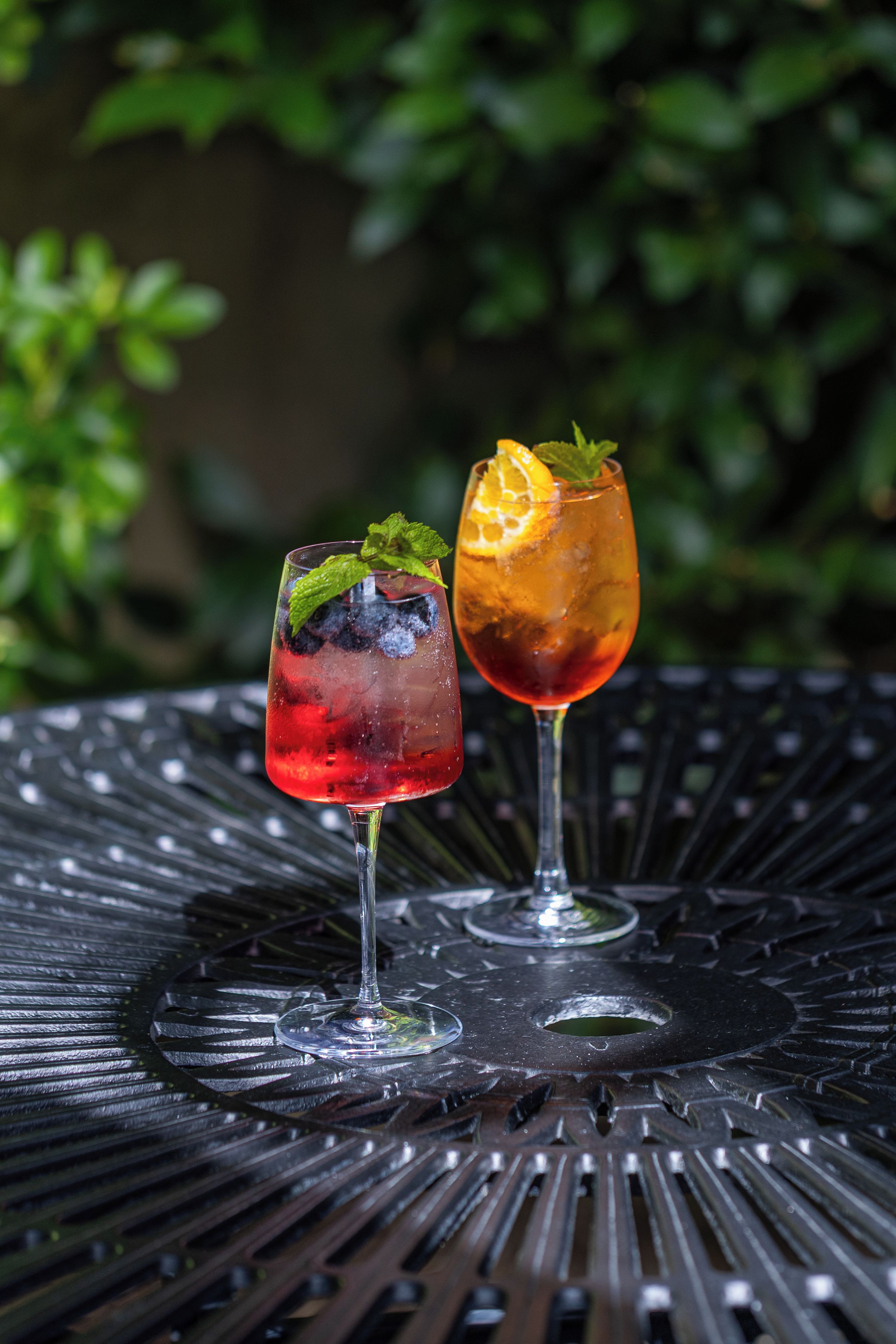 Two drinks on a metal table with a blurred green background.