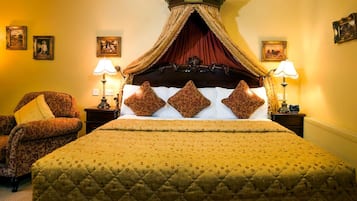Un dormitorio con una cama grande, dos mesitas de noche con lámparas, una silla y cuadros enmarcados en las paredes, además de un dosel decorativo.
