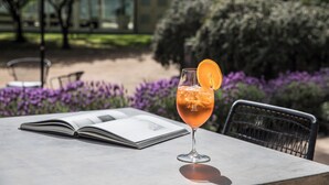 Un libro abierto sobre una mesa, con un vaso de bebida y una silla al fondo.