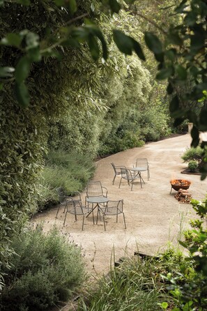 A patio with metal chairs and a fire pit surrounded by dense foliage. - Lancemore Lindenderry Red Hill (Red Hill)