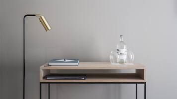 A minimalist desk with a lamp, a book, a glass bottle, and a glass.