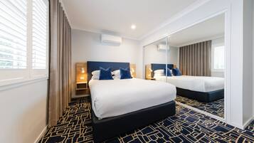 A hotel room with a large bed, a bedside table, a mirror, and a window with curtains.