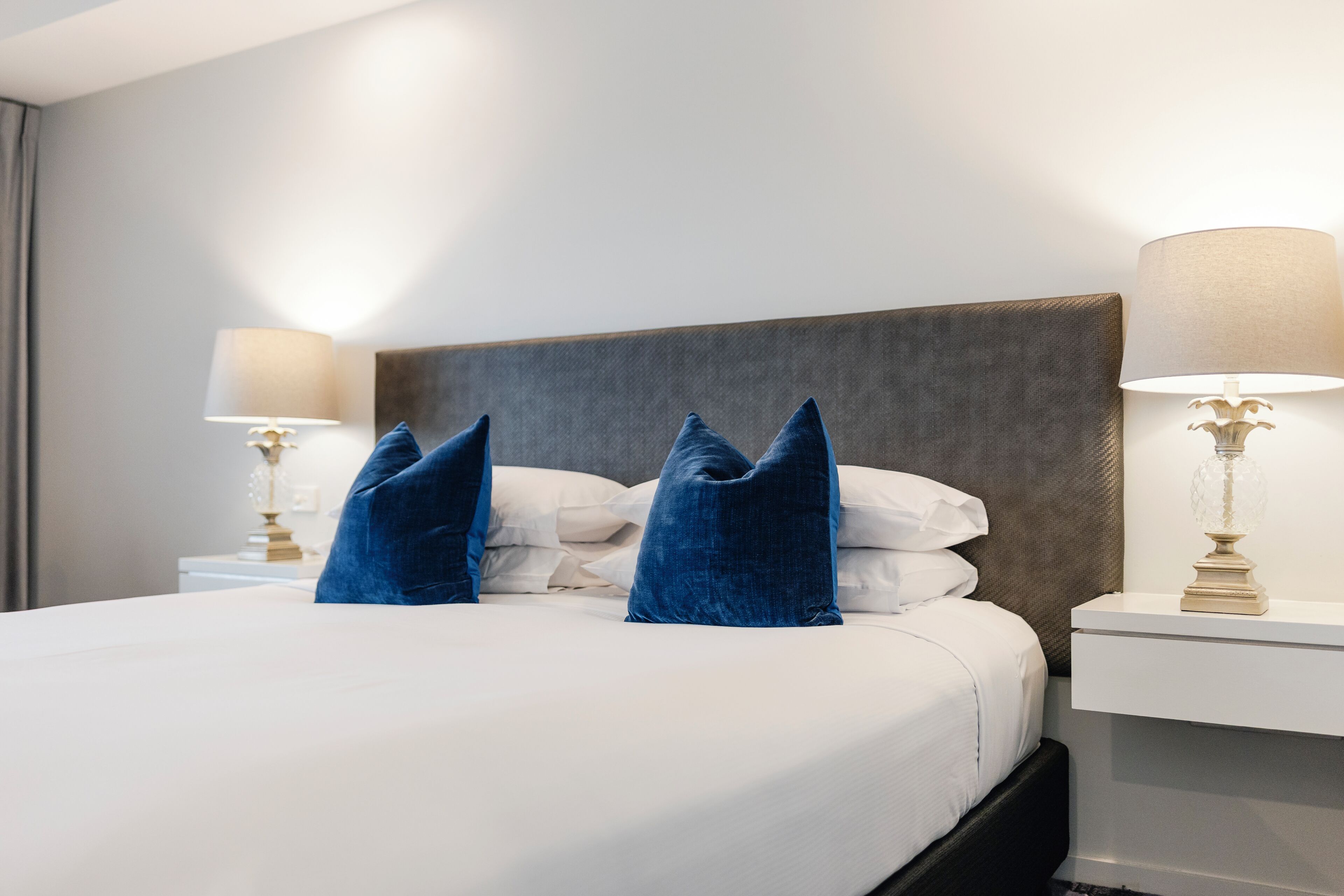 A hotel room with a large bed, two bedside lamps, and a headboard.