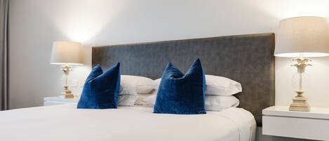 A hotel room with a large bed, two bedside lamps, and a headboard.