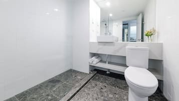 Un baño moderno con ducha de vidrio, inodoro blanco y encimera de mármol.