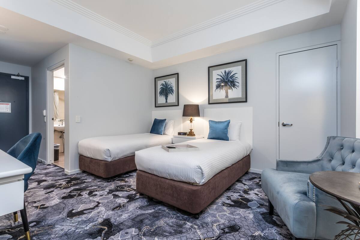 Habitación de hotel con dos camas, un escritorio, una silla y una mesa de comedor.