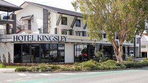 A modern hotel with a prominent 'HOTEL KINGSLEY' sign, large windows, and a landscaped front garden. - Hotel Kingsley (Hamilton)