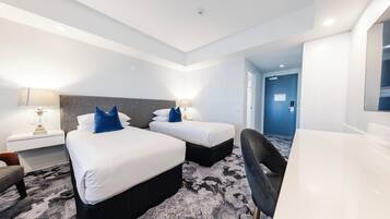 A hotel room with two beds, a desk, a chair, and a large mirror.