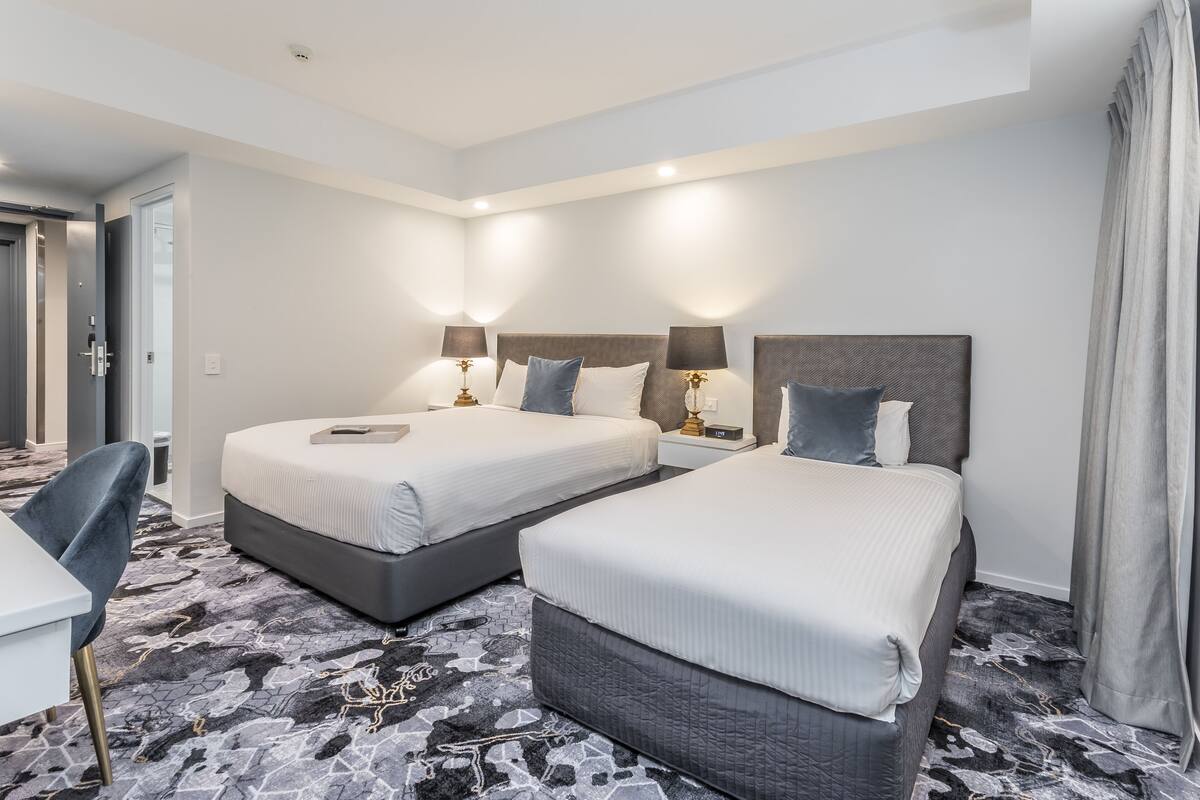 Habitación de hotel con dos camas, un escritorio y una silla.