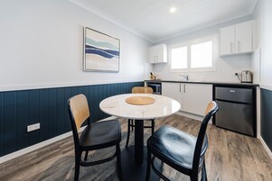A modern kitchen with white cabinets, a round marble table, and two black chairs.
