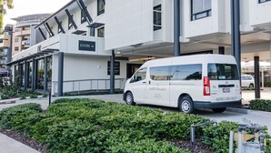 A modern building with an 'ENTRY' sign, a white van with 'HOTEL KINGSLEY' branding, and a clear pathway leading to the entrance. - Hotel Kingsley (Hamilton)