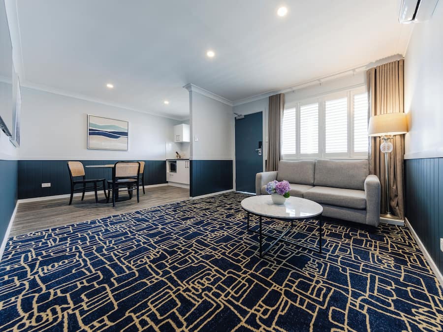 Une chambre d’hôtel comprenant un coin repas, un canapé, une table basse et une fenêtre avec des rideaux.