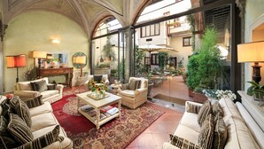 A spacious lobby with high ceilings, arched doorways, and a central seating area with sofas and a coffee table. - J And J Historic House Hotel (Florence)