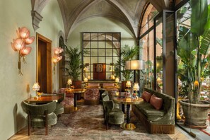 A lobby with a high arched ceiling, a central seating area with sofas and chairs, and a large window with a view of greenery. - J And J Historic House Hotel (Florence)