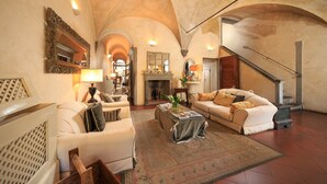 A spacious living room with high ceilings, a fireplace, and a staircase. - J And J Historic House Hotel (Florence)