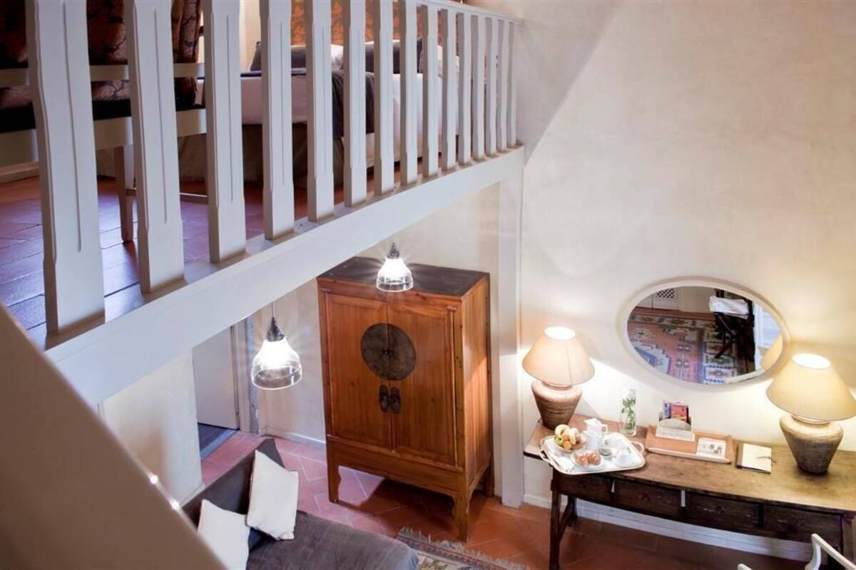 A staircase with a railing, a wooden cabinet, and a table with a lamp and a mirror.