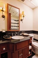 A bathroom with a large mirror, two wall-mounted lights, a sink, and a toilet.