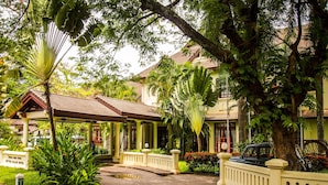 A traditional building with a tiled roof, surrounded by lush greenery and a paved walkway. - Settha Palace Hotel (Vientiane)