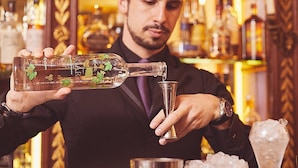 A bartender pouring a drink into a glass. - L'Hotel (Paris)