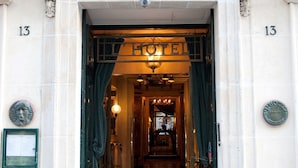 The entrance to a hotel with a grand archway, a chandelier, and a sign reading "HOTEL". - L'Hotel (Paris)