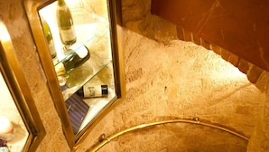 A spiral staircase with a glass enclosure at the top, leading to a room with a stone wall and a window. - L'Hotel (Paris)