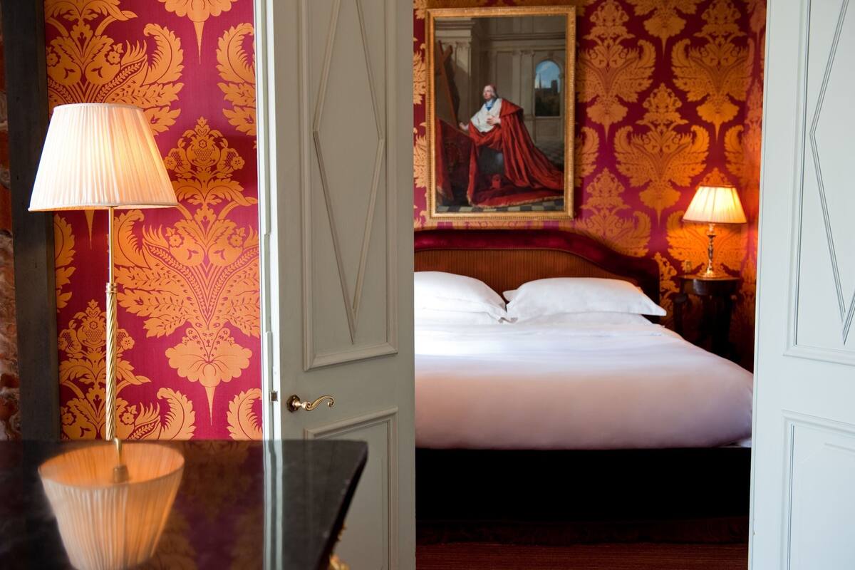 A hotel room with a bed, two lamps, and a painting on the wall.