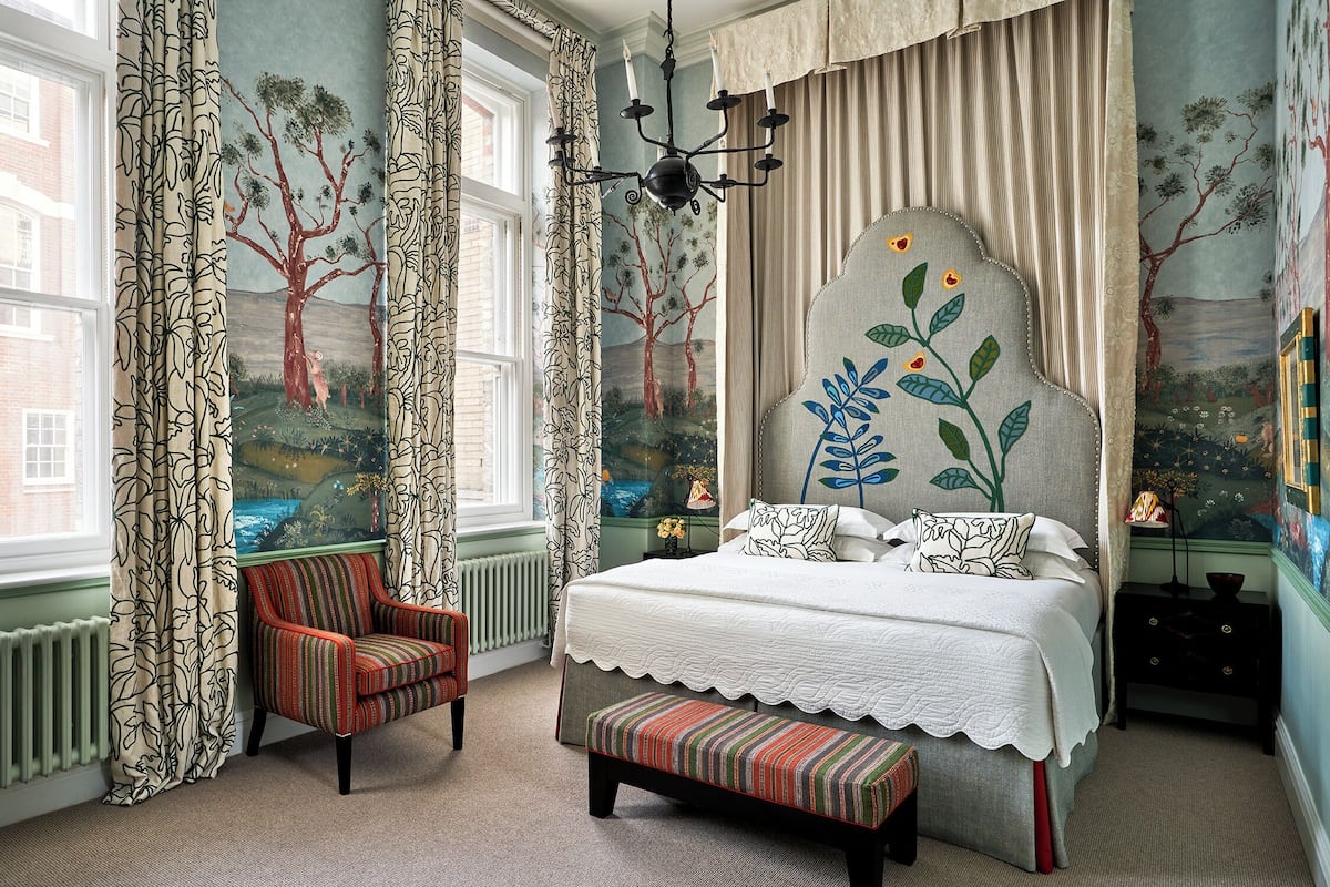 A bedroom with a large bed, a chair, a bench, and a nightstand.