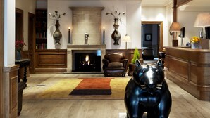 Un salón amplio con chimenea, una gran escultura negra y piso de madera.