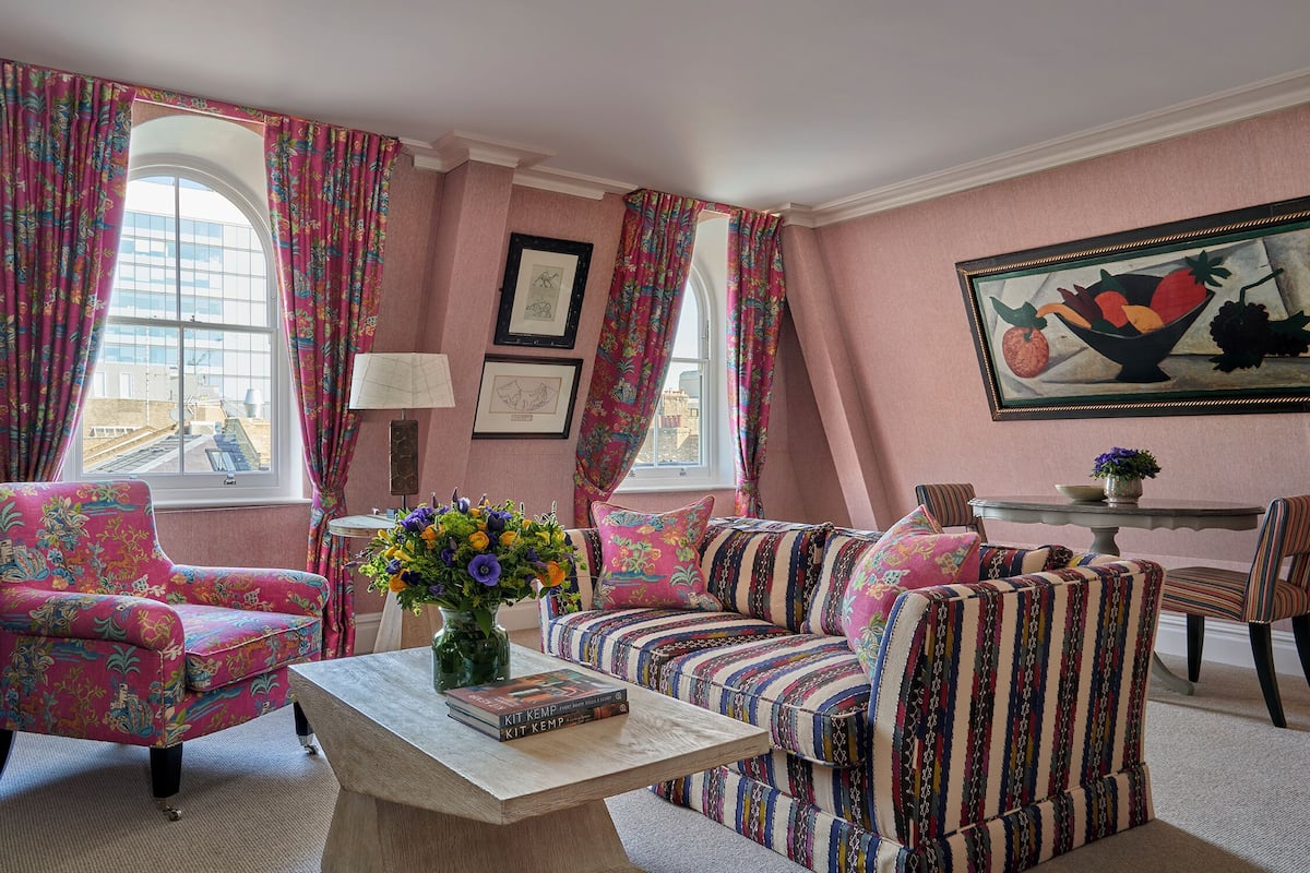 A cozy living room with a sofa, armchairs, a coffee table, and a painting on the wall.