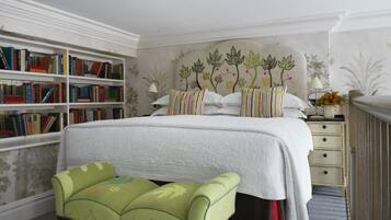 A bedroom with a large bed, a bookshelf, a nightstand, and a green upholstered bench.