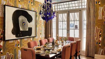 Una sala da pranzo con un tavolo apparecchiato per sei persone, un lampadario e carta da parati decorata.