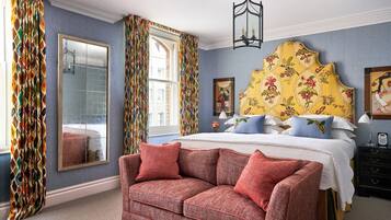 A bedroom with a large bed, a mirror, a red sofa, and a patterned headboard.