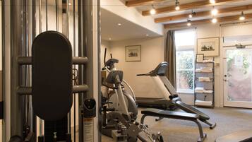 A gym with exercise equipment, a treadmill, and a bench.