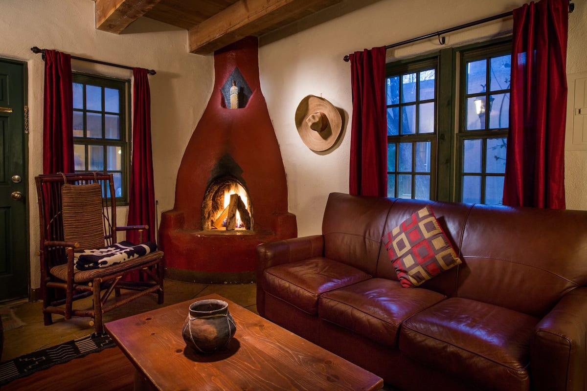 A cozy room with a fireplace, leather sofa, wooden table, and a chair.