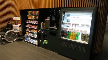 A vending machine with snacks and drinks, a wheelchair, and a 'Welcome' sign.