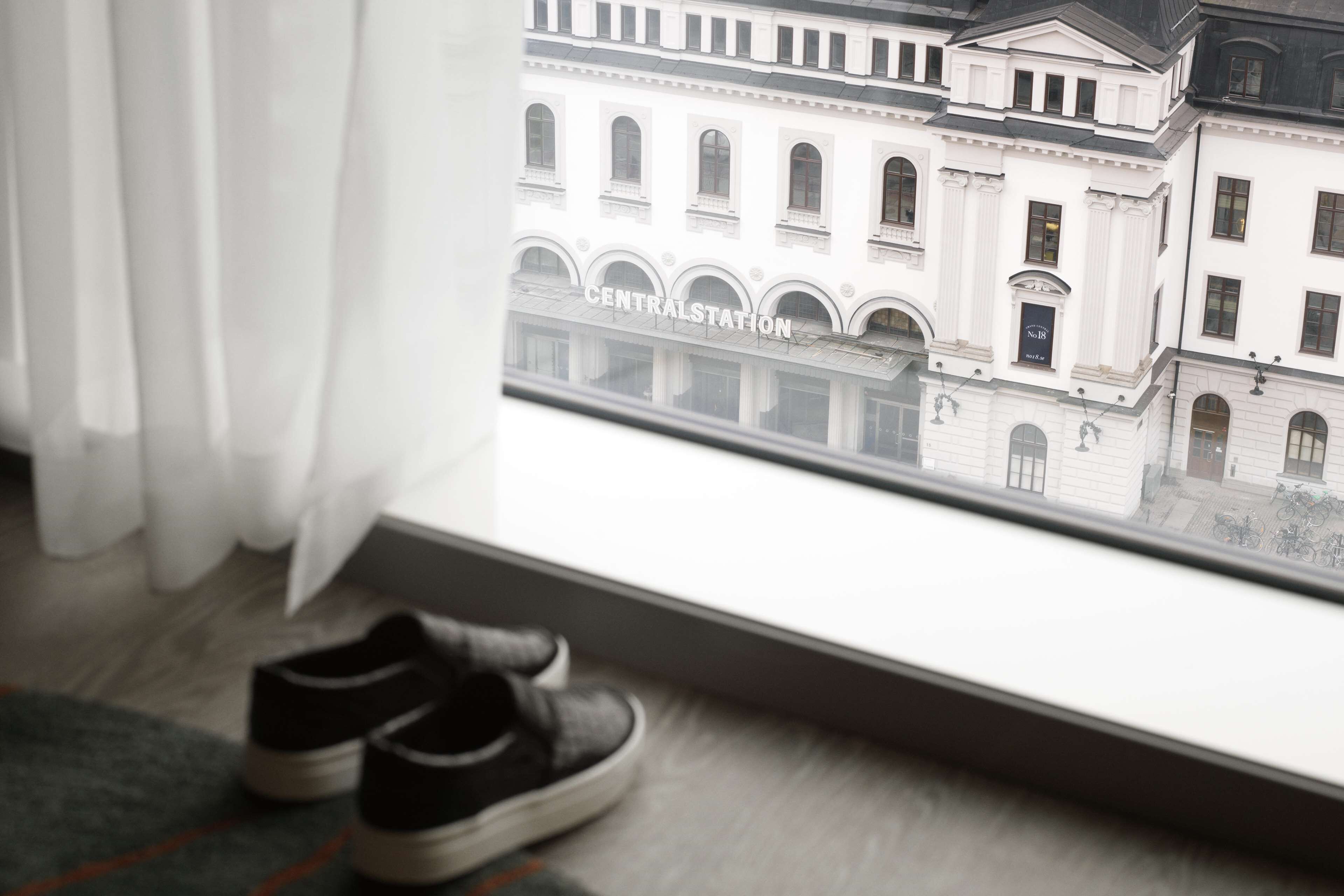 A pair of shoes on a window sill, a view of a building labeled 'CENTRAL STATION,' and a curtain partially drawn.