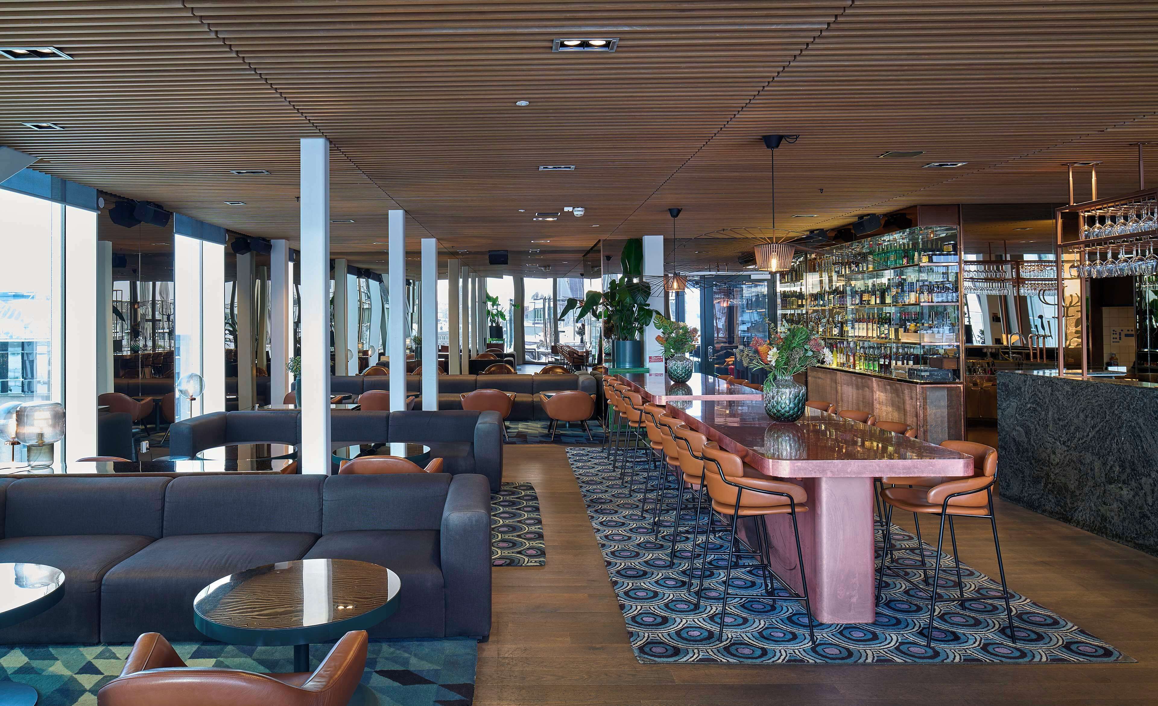 A modern bar area with seating, a bar counter, and a view of the city.