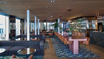 A modern bar area with seating, a bar counter, and a view of the city.