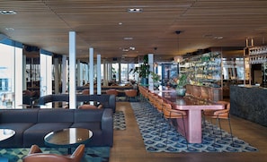 A modern bar area with seating, a bar counter, and a view of the city.