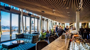 A modern bar area with seating, large windows, and a city view. - Scandic Continental (Stockholm)