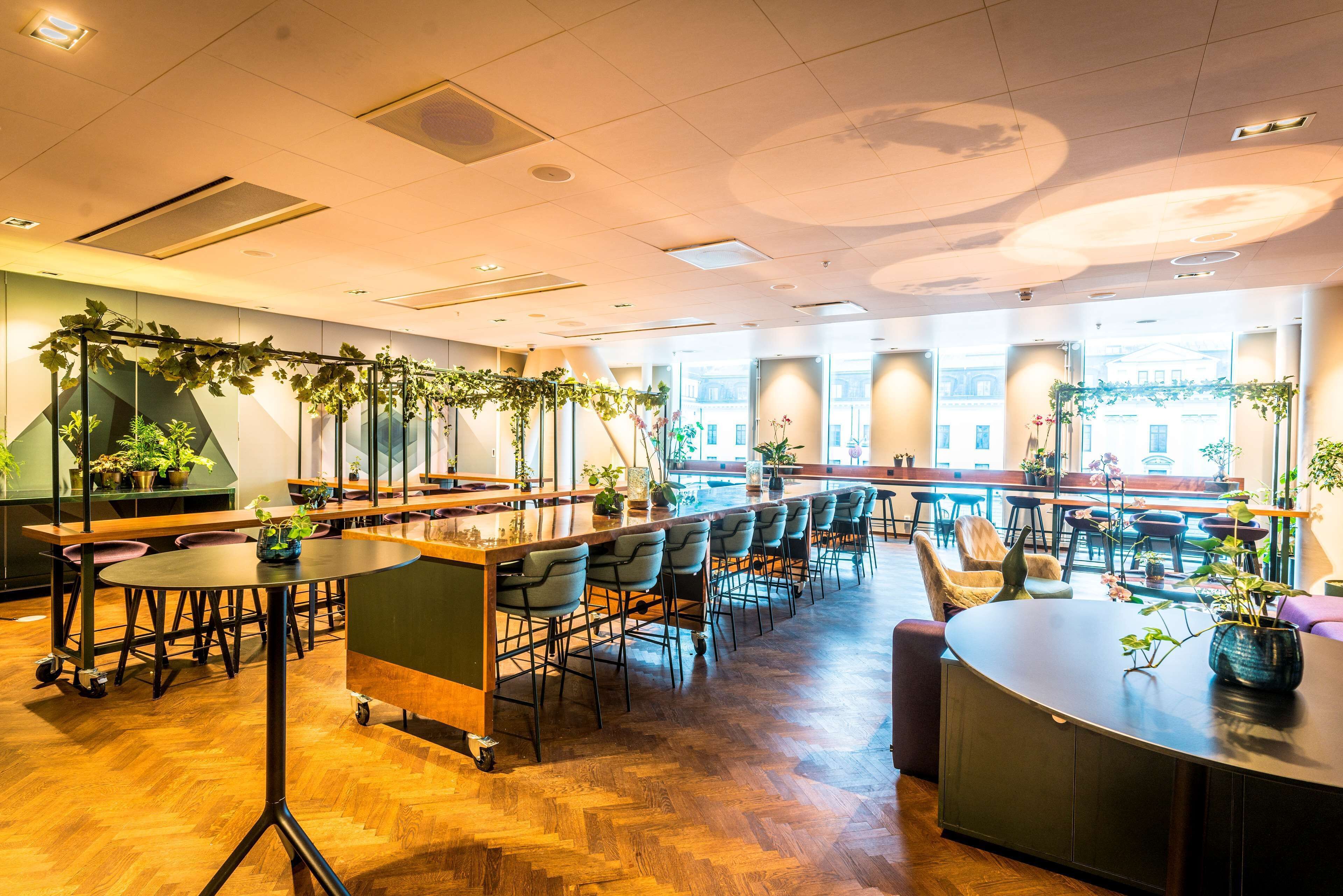 A modern restaurant with a long counter, multiple seating areas, and large windows.