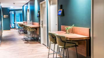 A hallway with multiple bar seating areas, each with a wooden table and a chair.