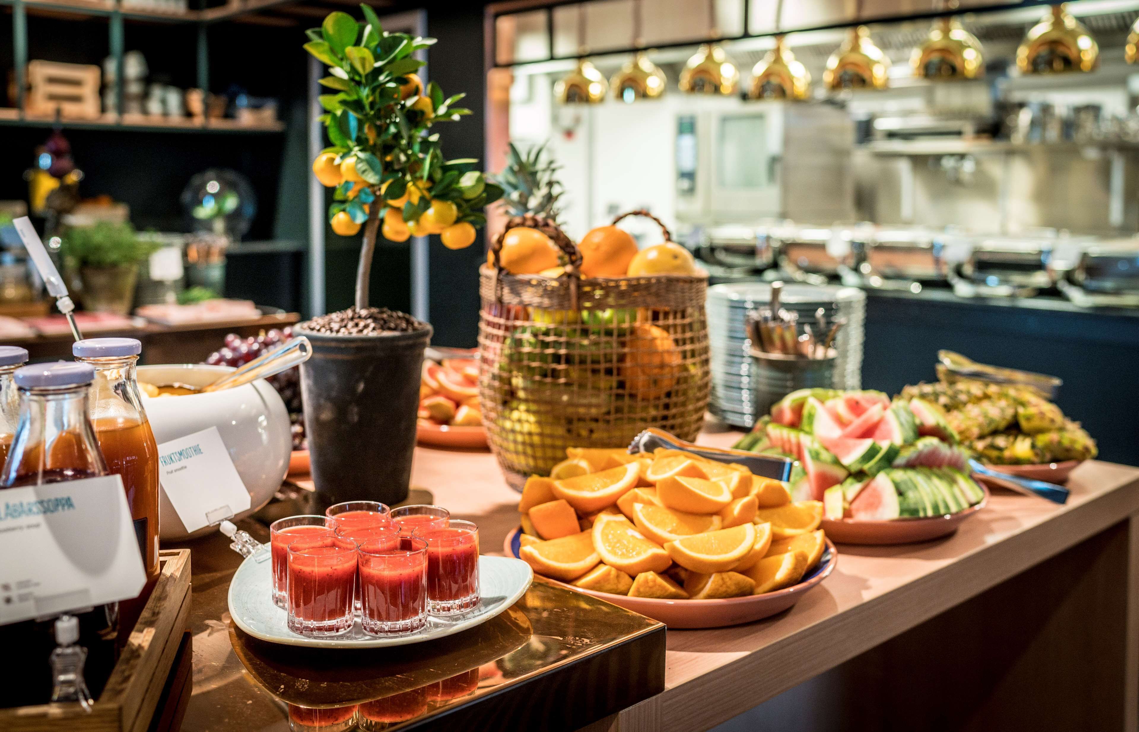 Un buffet con diverse varietà di frutta, succhi e una pianta decorativa.