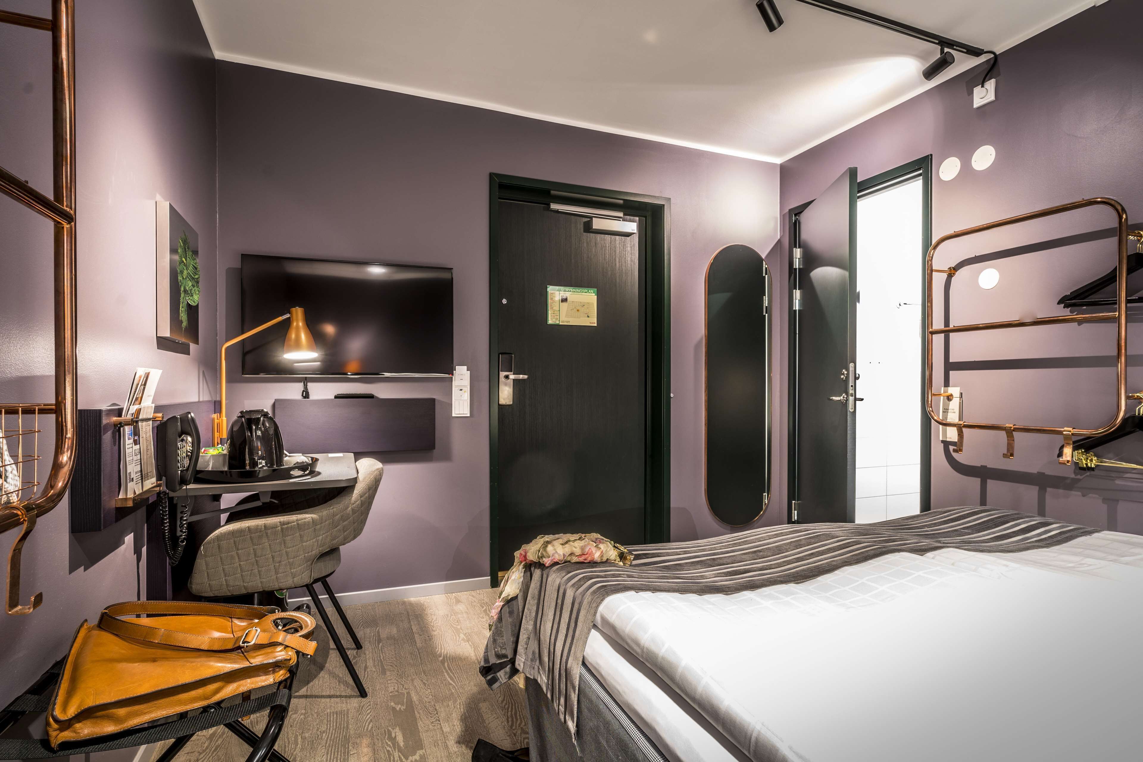 Una habitación de hotel moderna con cama, escritorio, silla y televisor.